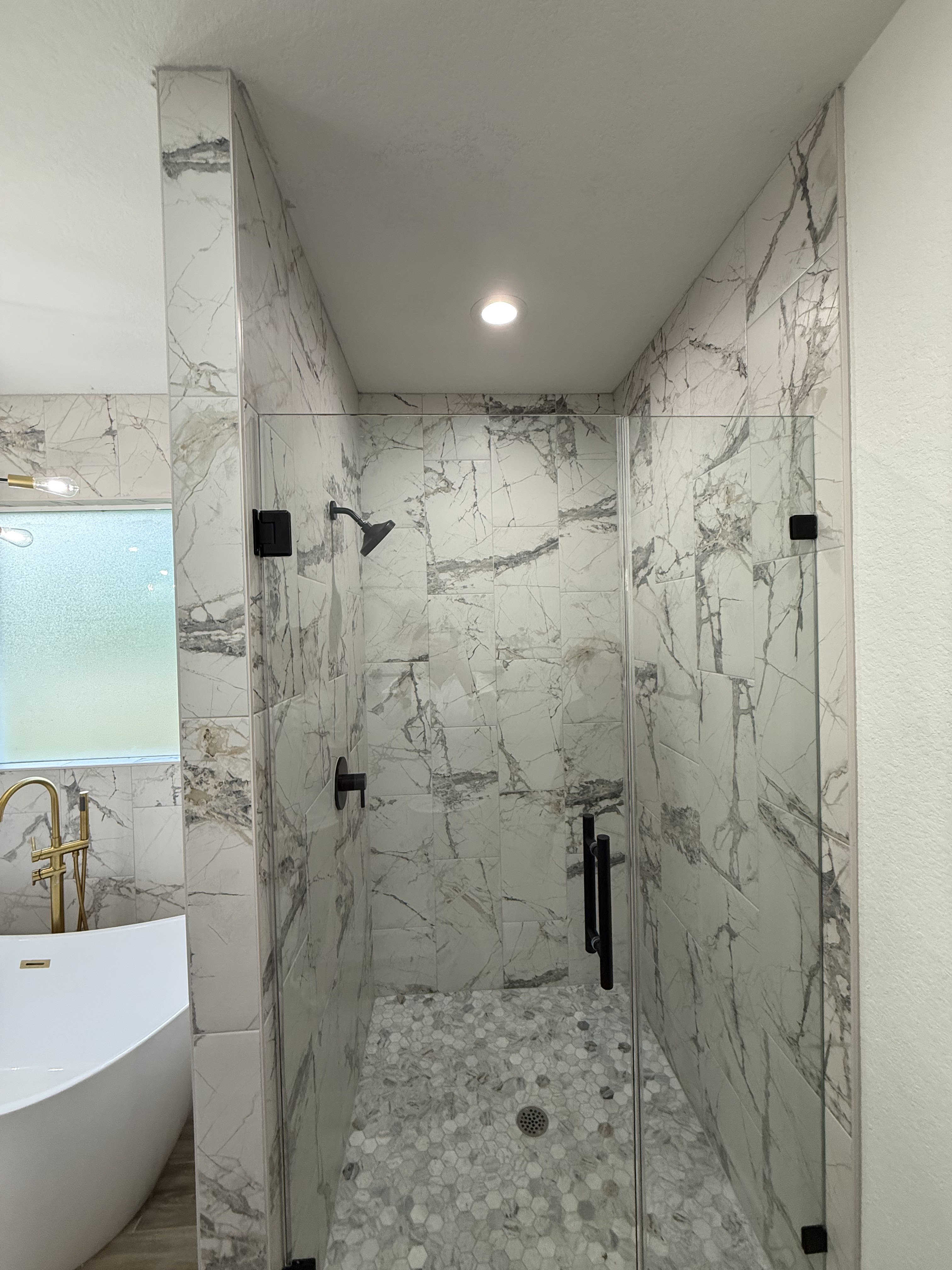 Marble-tiled walk-in shower with freestanding tub