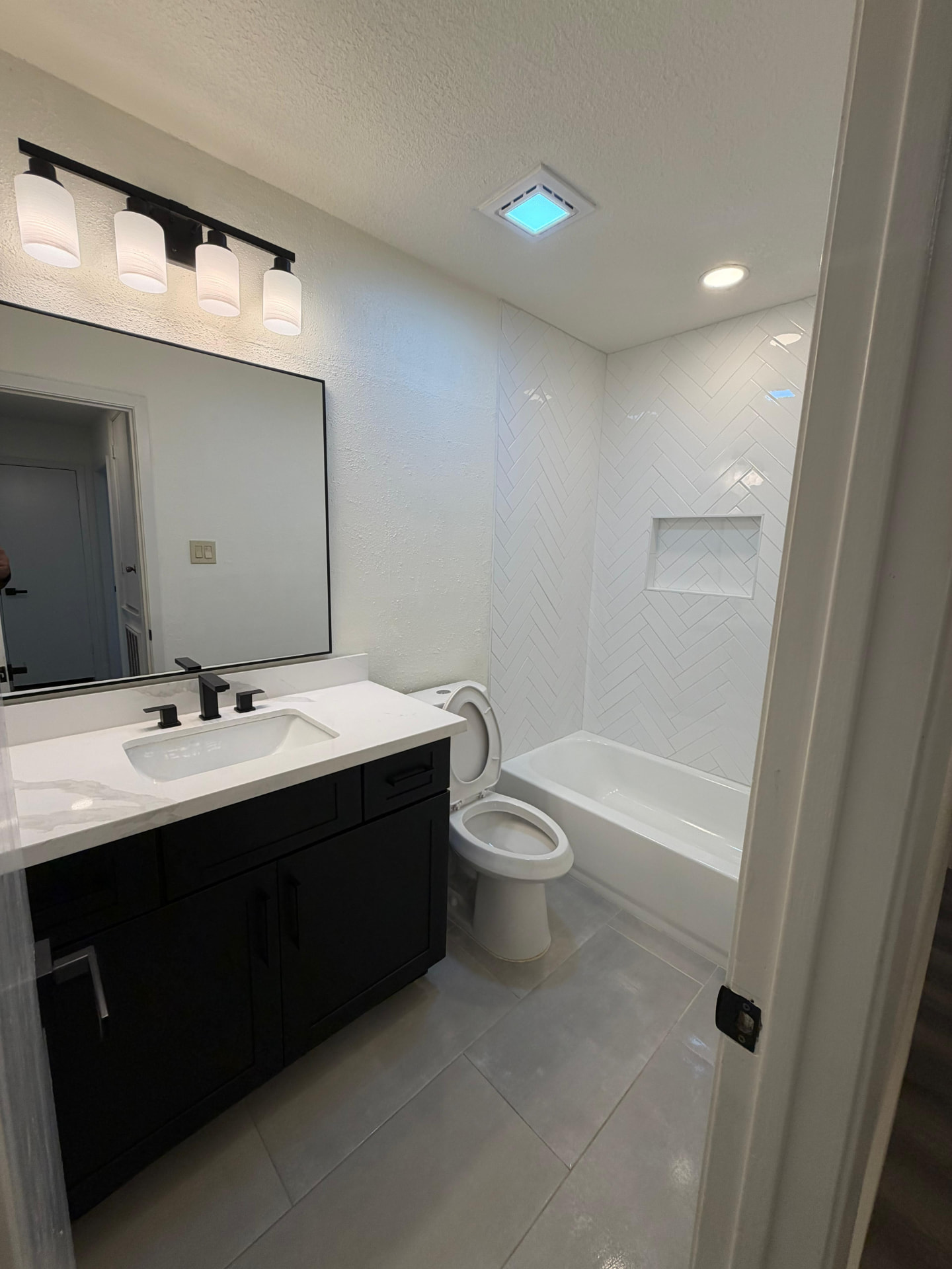 Bathroom remodel with herringbone tile and black vanity